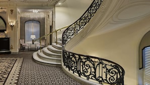 Una gran escalera ornamentada con barandales negros intrincados y una alfombra estampada.