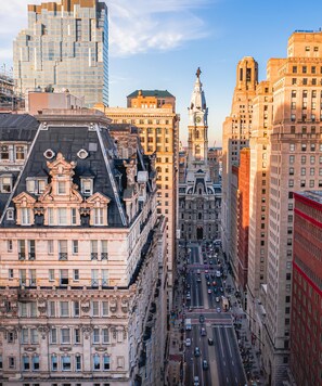 Un paisaje urbano con edificios históricos, una imponente torre del reloj y una calle concurrida.