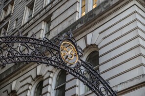 Enter a historic building with a classical architectural style, featuring stonework and arched windows.