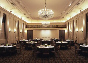 Formal events and gatherings take place in this grand banquet hall with high ceilings, intricate moldings, and ornate chandeliers.