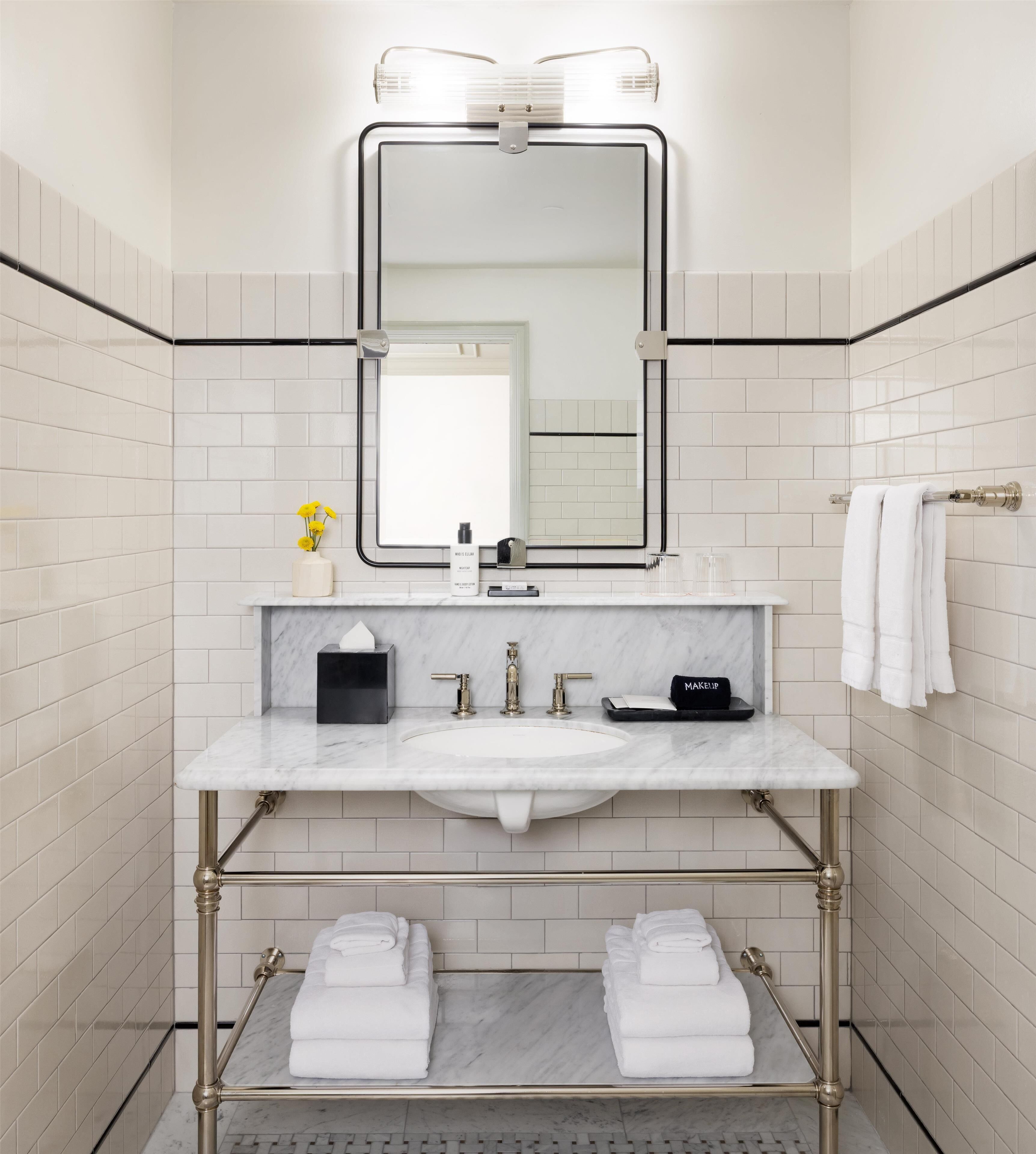 A bathroom with a white sink, a mirror, and a towel rack.