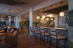 A bar area with high stools, hanging pendant lights, and a bar counter.