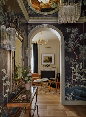 An interior with a grand mirror, chandelier, and a fireplace.
