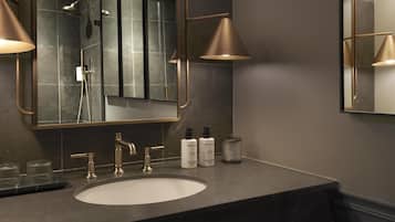 Un baño moderno con un espejo grande, dos lámparas colgantes, un lavabo y una ducha.