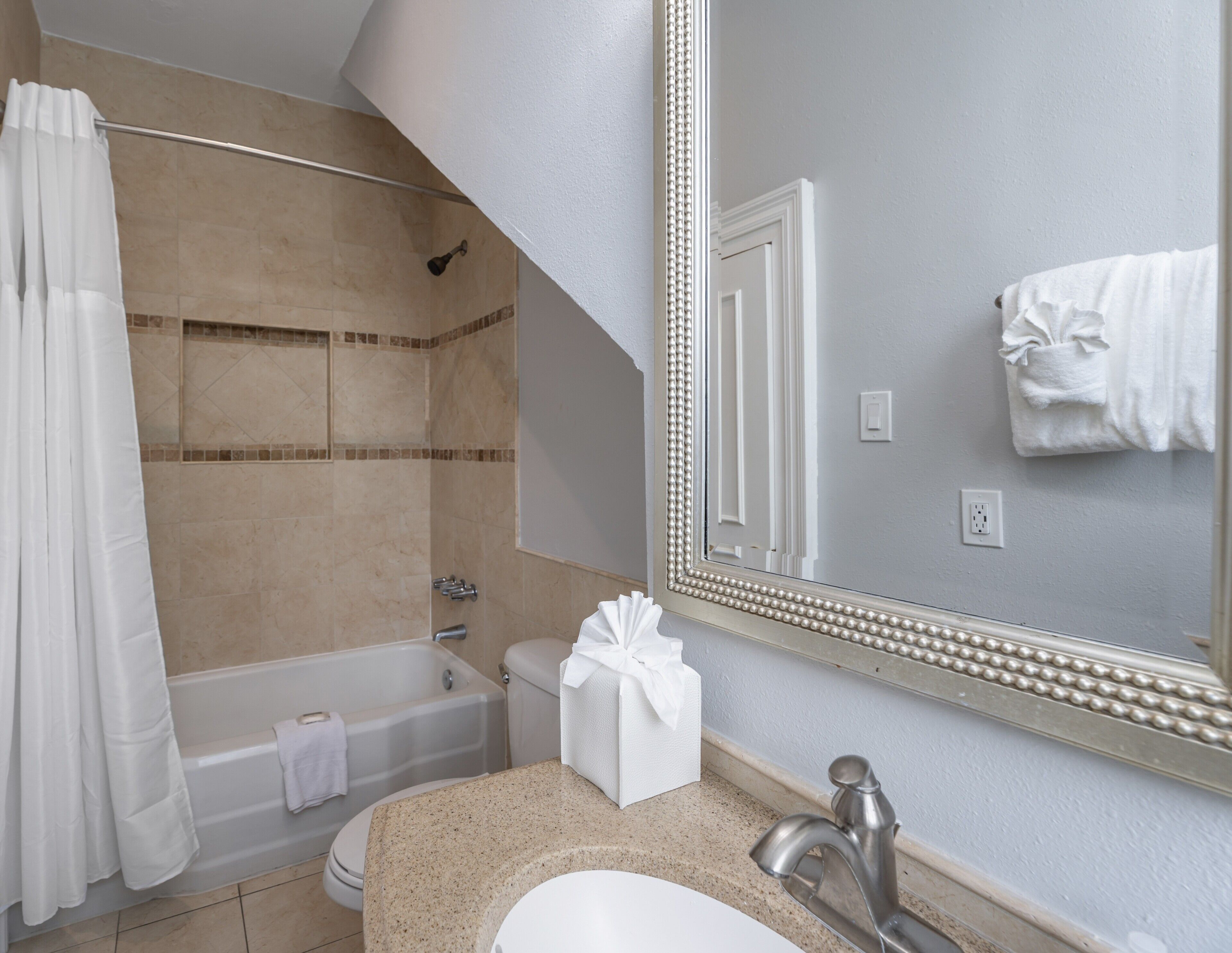 Un baño con ducha, bañera, inodoro, lavabo y un espejo grande.