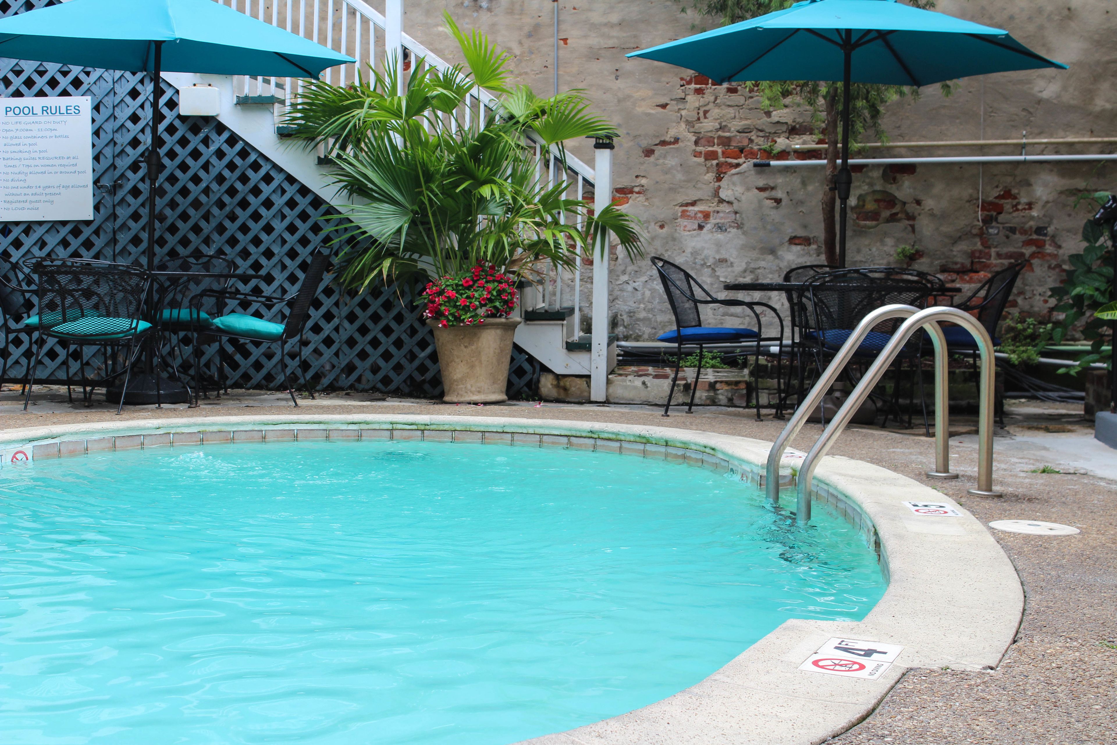 Une piscine bordée de bleu, entourée de chaises et de parasols.