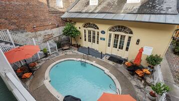 A rooftop pool area with a pool, lounge chairs, and umbrellas.