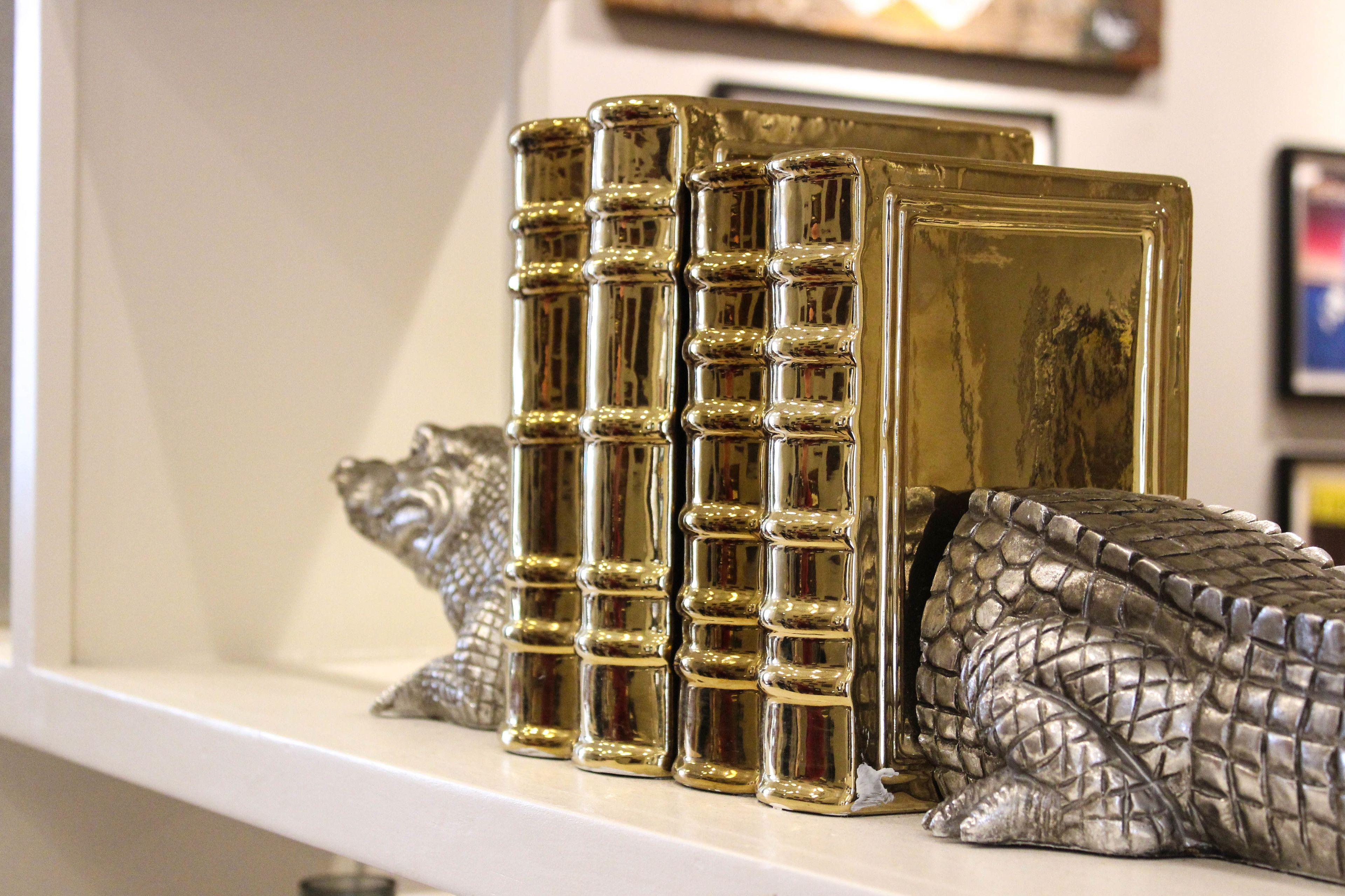 A shelf with decorative books and a silver sculpture.