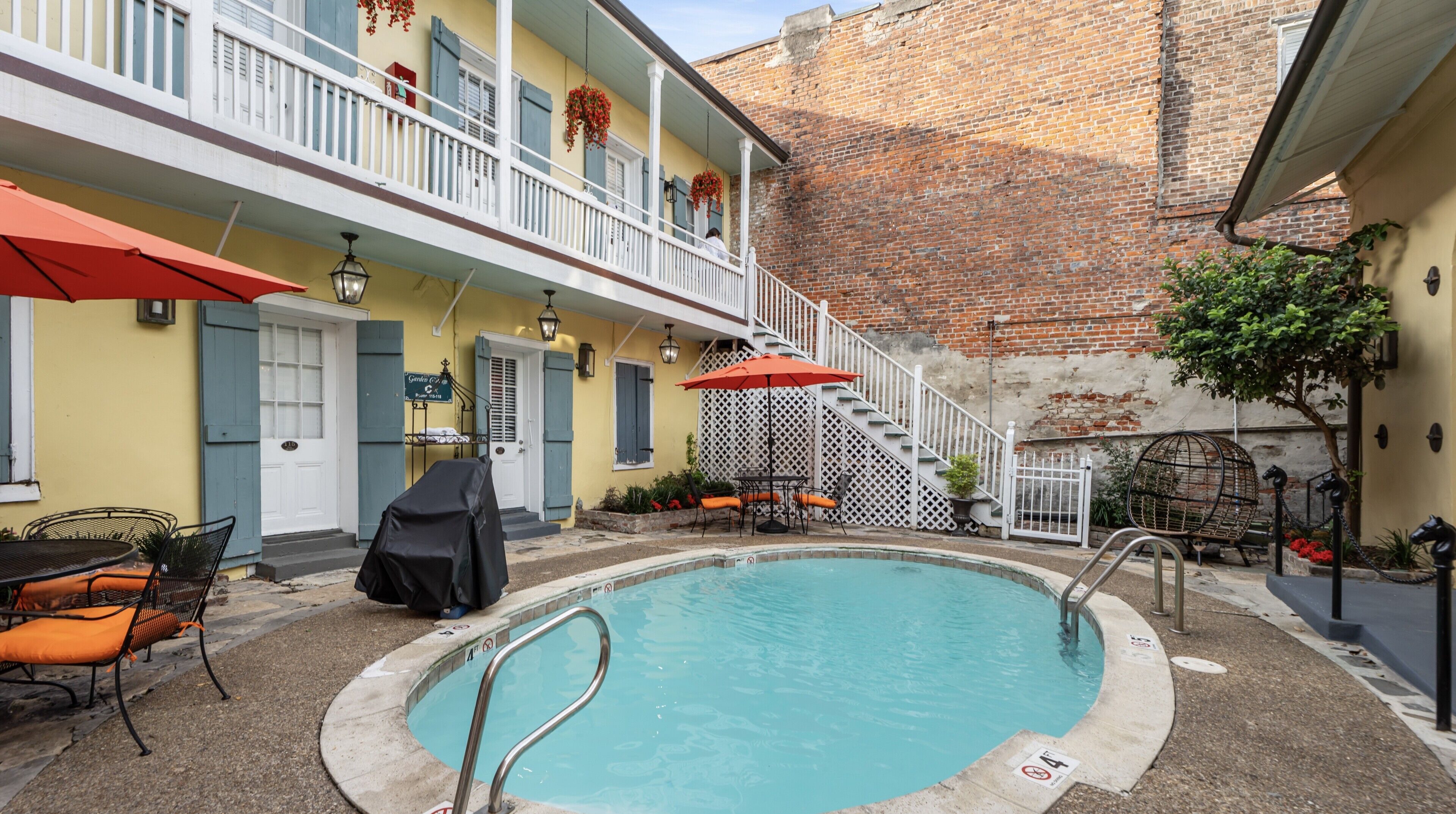 A pool area with a covered seating area, a staircase, and a building with a brick wall.