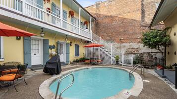 A pool area with a covered seating area, a staircase, and a building with a brick wall.