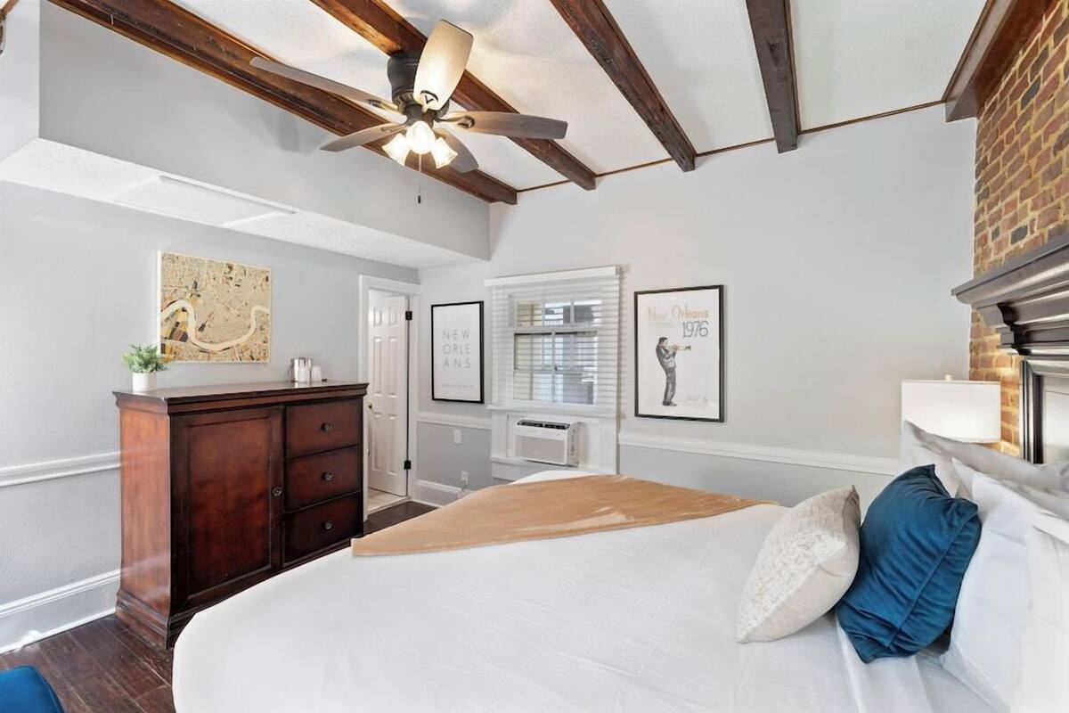 Un dormitorio con cama, ventilador de techo, cómoda y cuadros en la pared.