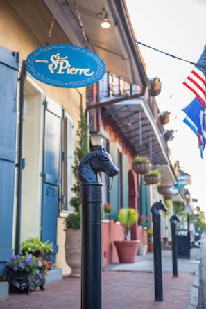 A street view with a hotel sign, a horse statue, and hanging plants. - Hotel St. Pierre®, a French Quarter Inns® Hotel (New Orleans)