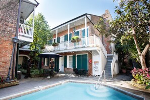 A pool area with a two-story building, outdoor seating, and a staircase leading to the upper level. - Hotel St. Pierre®, a French Quarter Inns® Hotel (New Orleans)