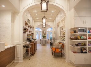A spacious hallway with a central seating area, a kitchen counter, and a microwave on the right. - Hotel St. Pierre®, a French Quarter Inns® Hotel (New Orleans)