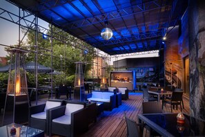 Un patio al aire libre con mobiliario de mimbre y una zona de bar.