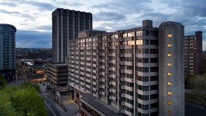Ein modernes Hochhaus mit mehreren Stockwerken, großen Fenstern und einer markanten Eckstruktur.