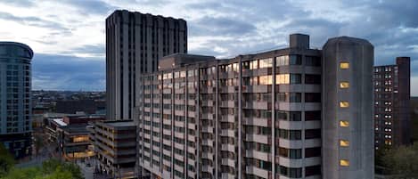 A modern high-rise building with multiple floors, large windows, and a prominent corner structure.