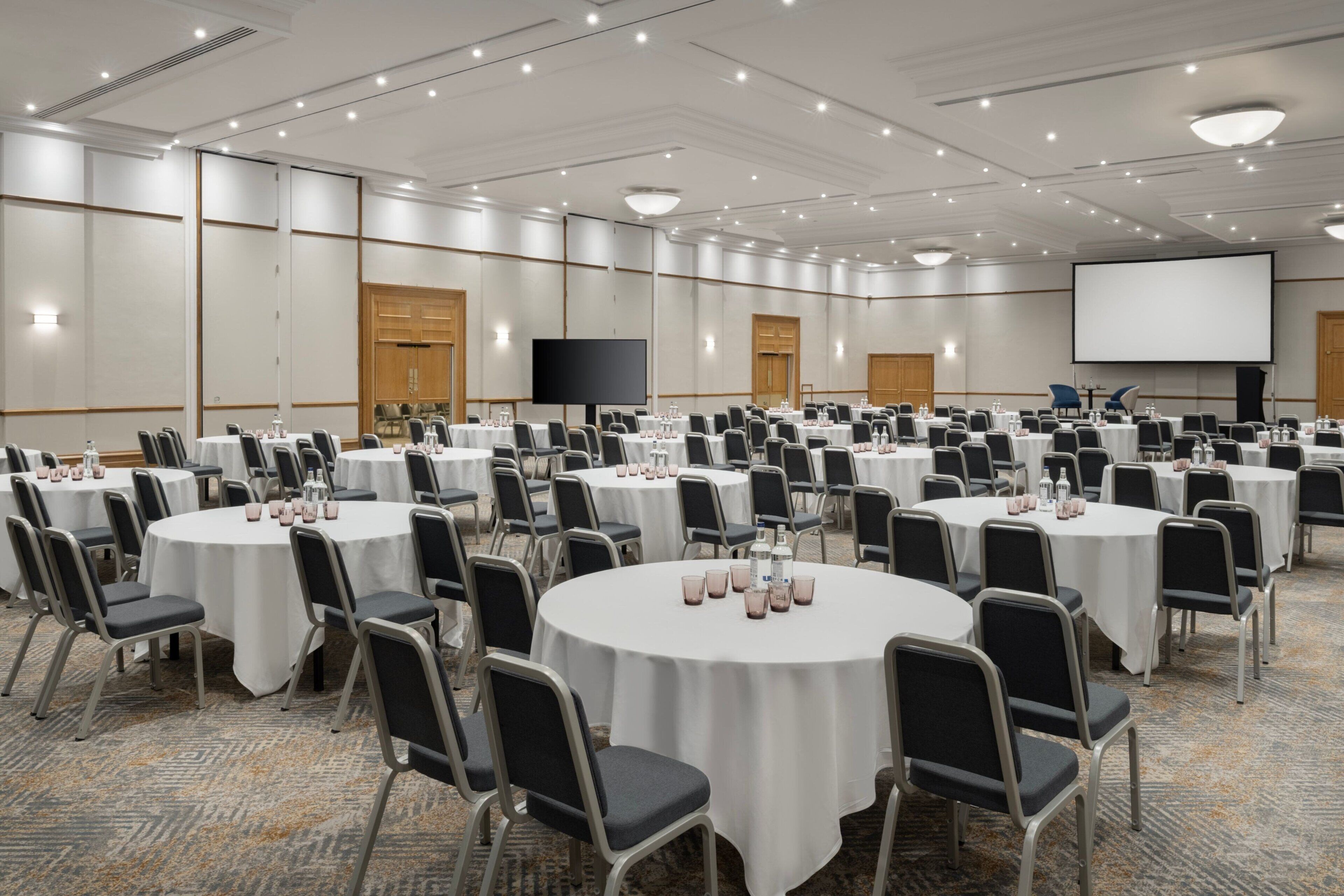 A conference room with multiple round tables, each set with chairs and water glasses.