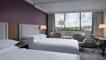 Une chambre d’hôtel avec deux lits, un bureau, une chaise et une vue sur la ville.