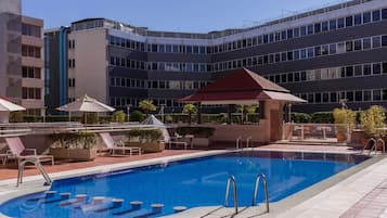 Una piscina al aire libre, sombrillas, tumbonas