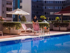 Una piscina al aire libre, sombrillas, sillones reclinables de piscina