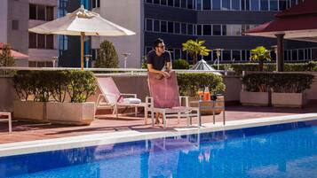 Una piscina al aire libre, sombrillas, tumbonas