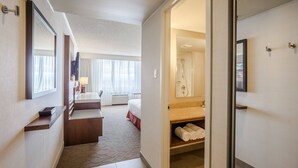 Une chambre d’hôtel avec un lit, un bureau, une salle de bain avec douche et une vue sur l’extérieur.
