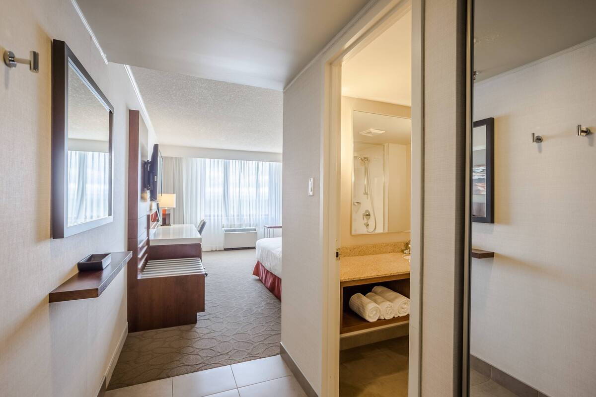 Ein Hotelzimmer mit Bett, Schreibtisch, Badezimmer mit Dusche und Blick ins Freie.