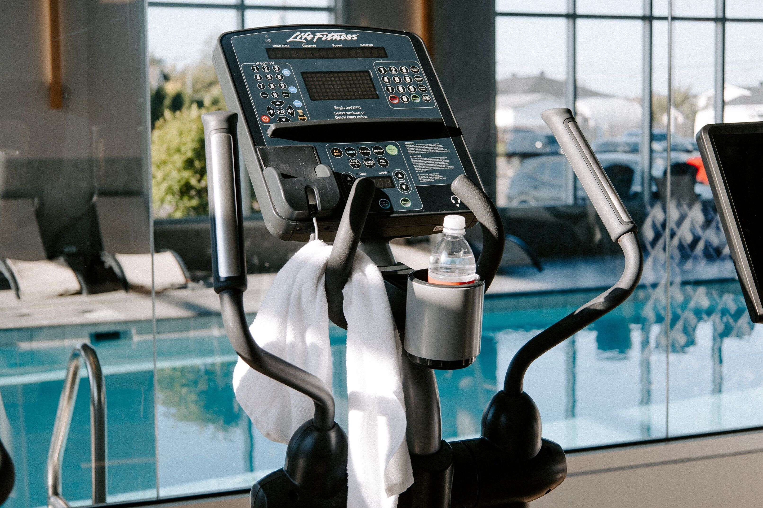 A treadmill with a control panel, a water bottle holder, and a towel.