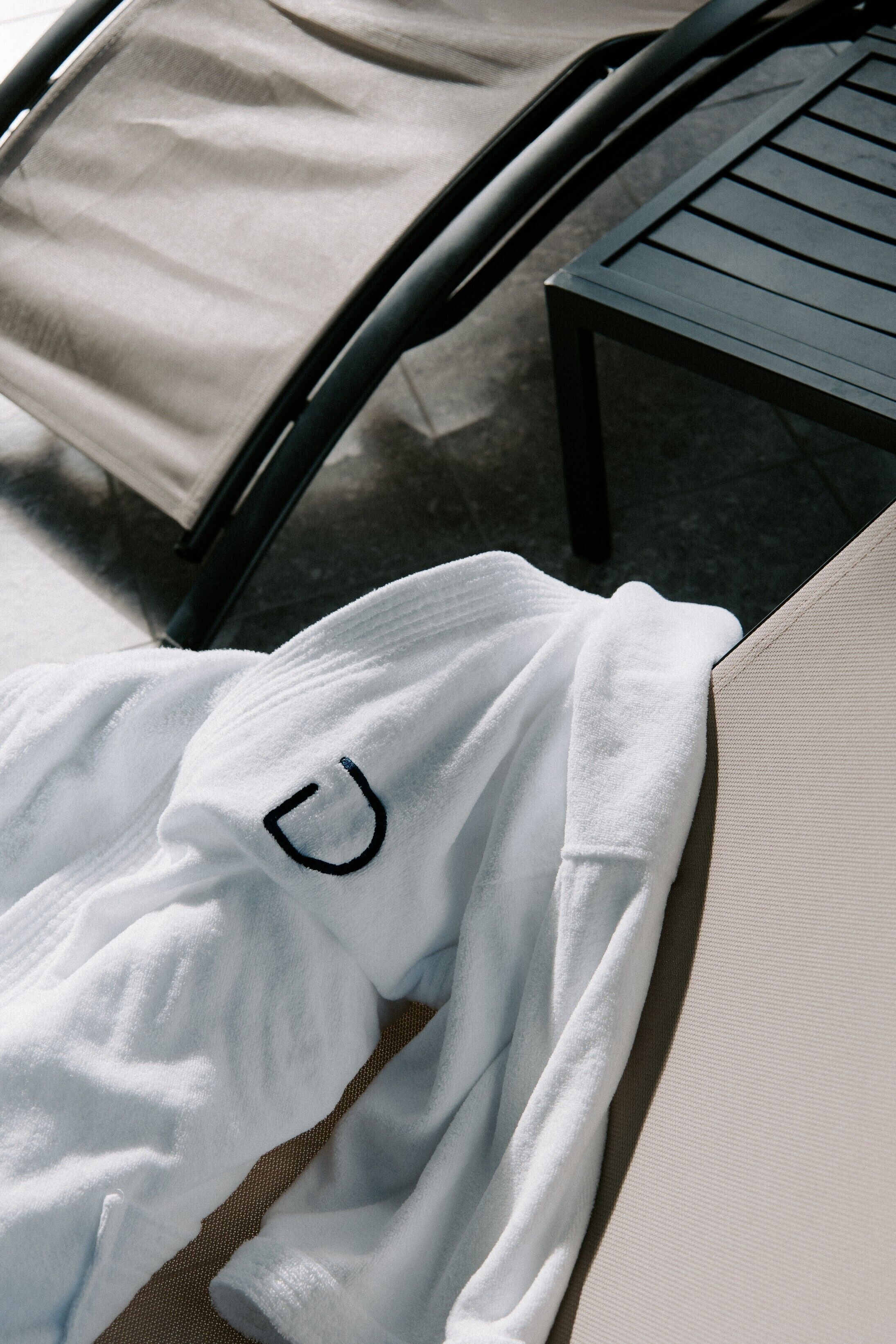 A white towel with a black logo on a lounge chair.