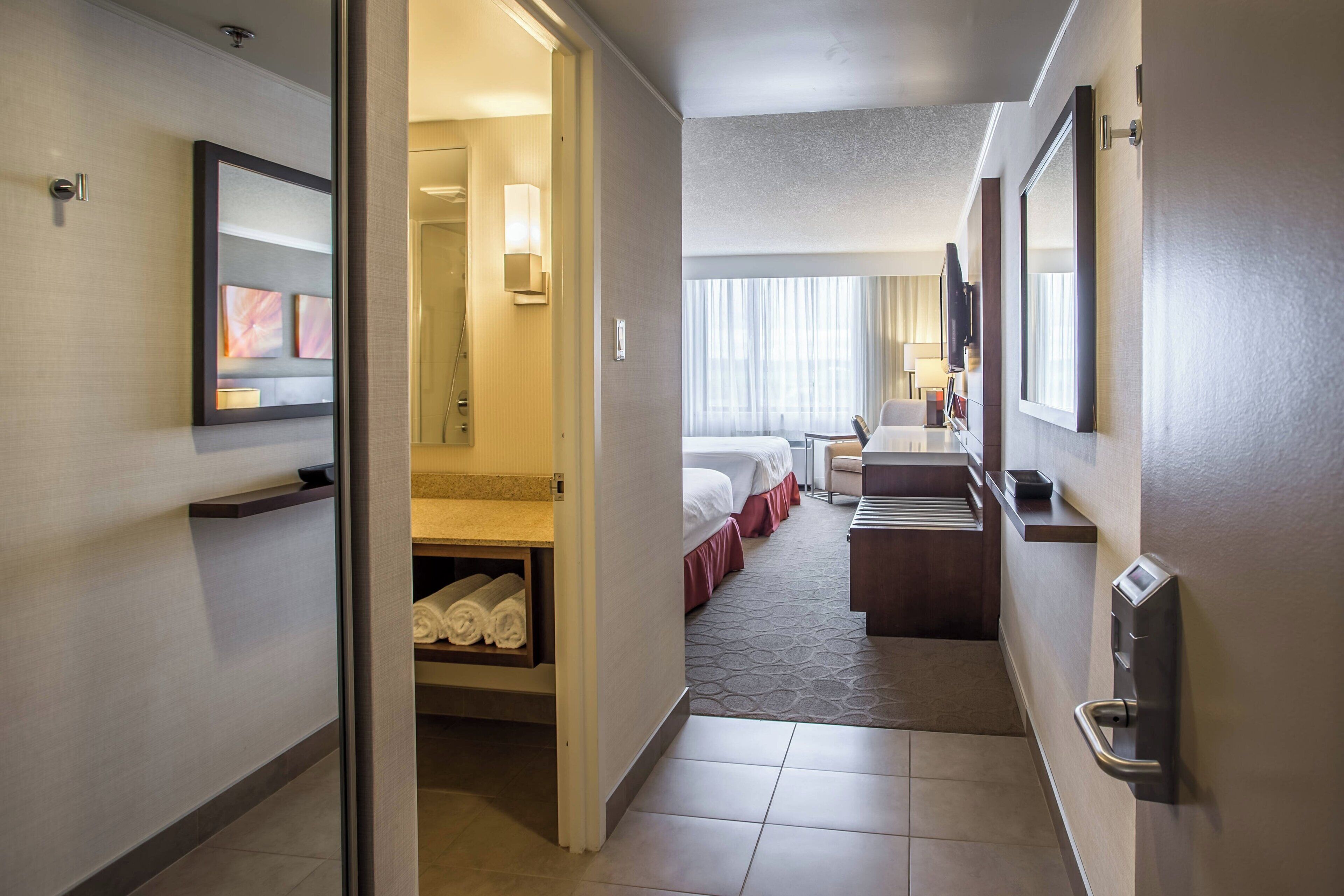Een hotelgang met een bed, bureau en een badkamer.