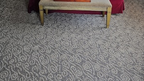 Una cama bien hecha con cabecera de madera, una mesita de noche con lámpara y una bandeja con toallas dobladas.