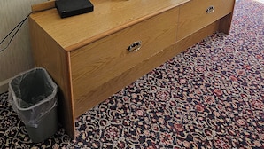 Un aparador de madera con un televisor de pantalla plana, una lámpara y un control remoto encima.