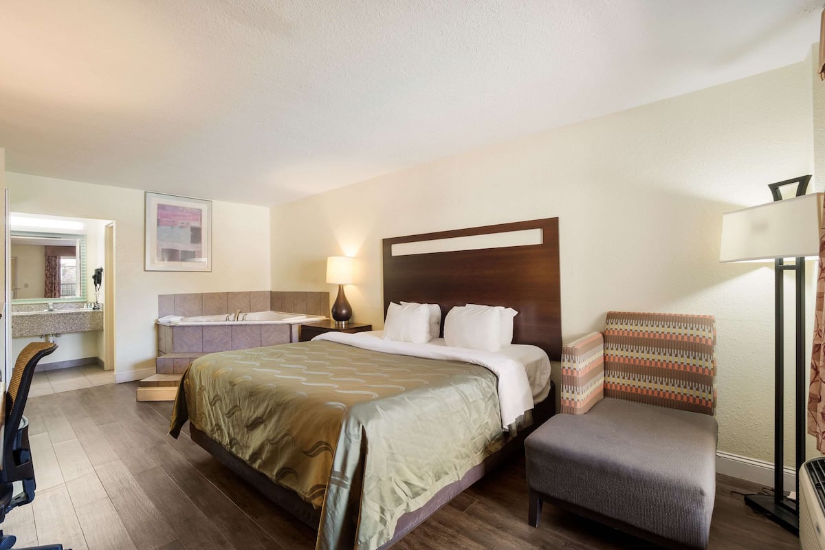 Una habitación de hotel con una cama grande, una silla, un escritorio y un baño.
