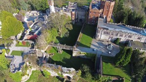 An aerial view of a historic estate with a central courtyard, stone buildings, and a bridge. - Ruthin Castle Hotel (Ruthin)