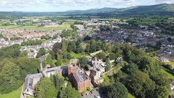 An aerial view of a town with a prominent castle-like building surrounded by greenery and residential areas.