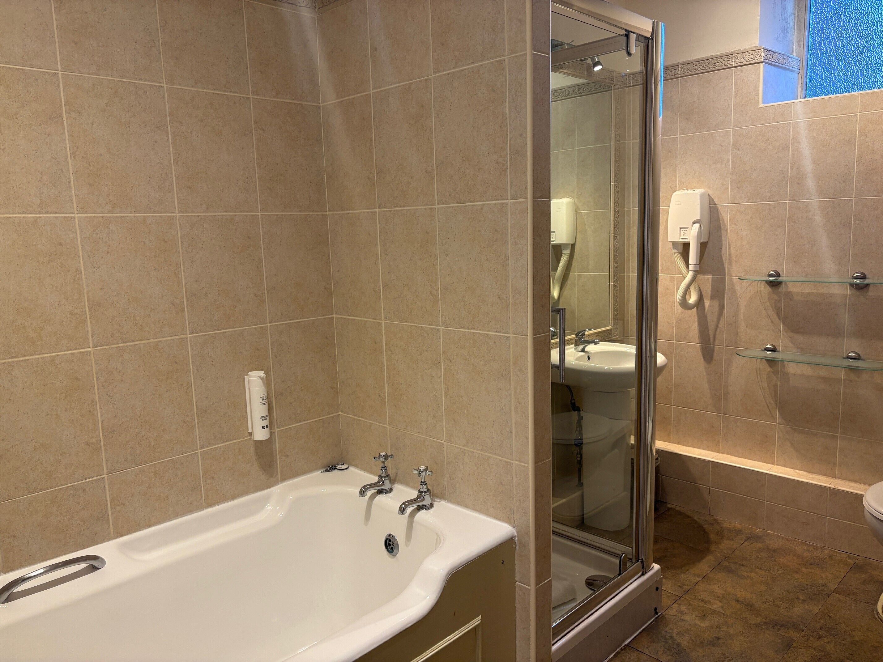 Un baño con ducha envuelta en vidrio, bañera blanca y lavabo.
