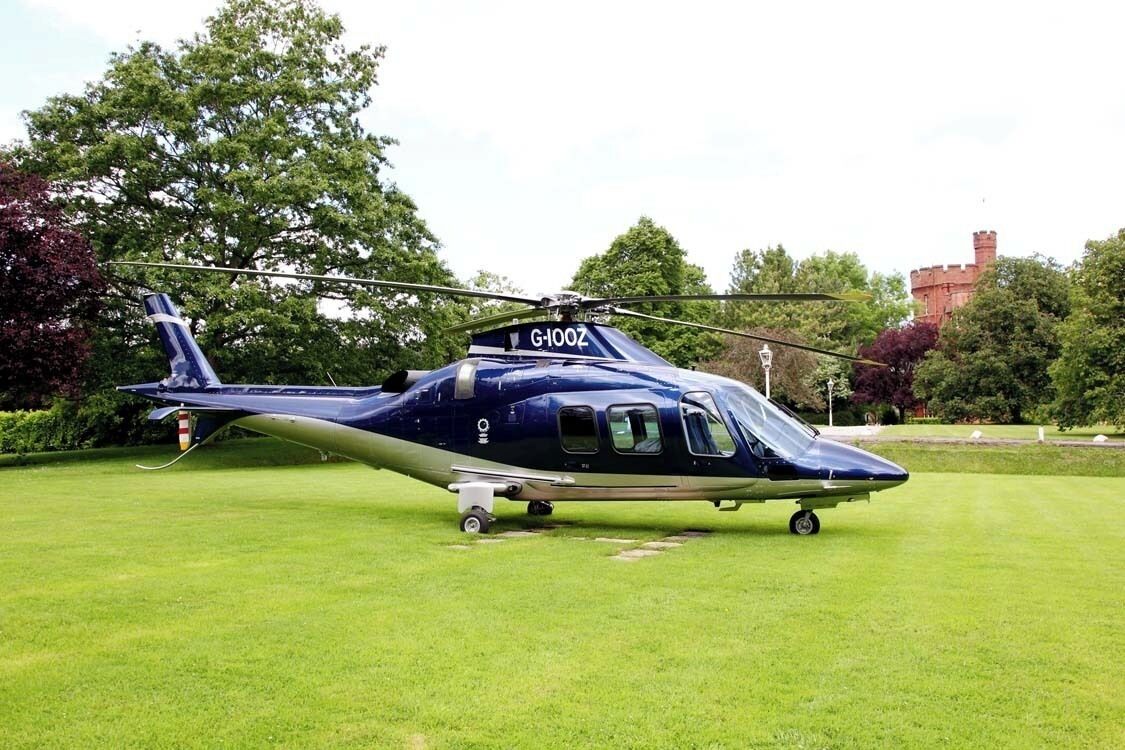 A helicopter with registration G-100Z parked on a grassy field.