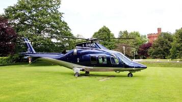A helicopter with registration G-100Z parked on a grassy field.