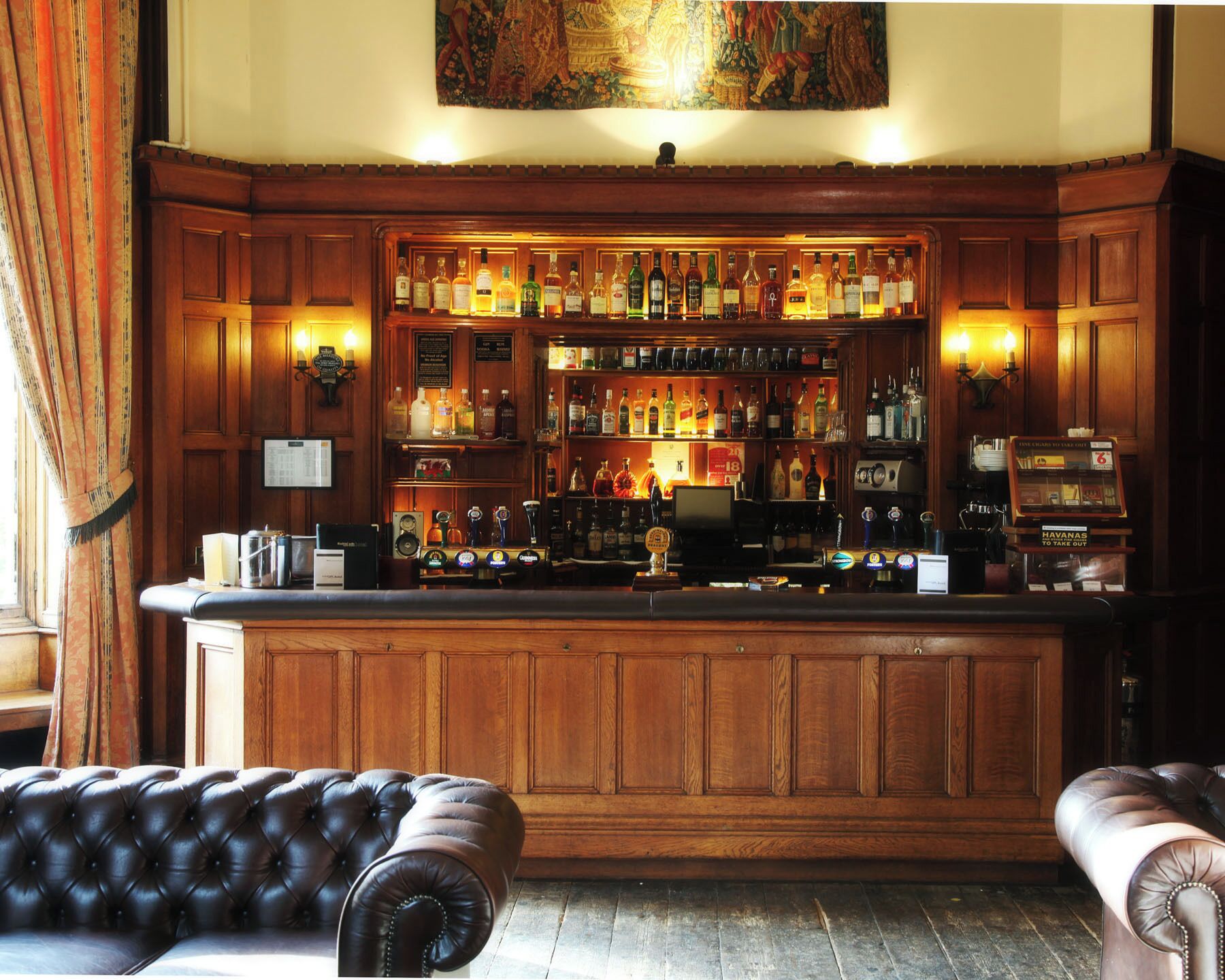 A bar area with wooden paneling, a variety of liquor bottles, a jukebox, and a cash register.