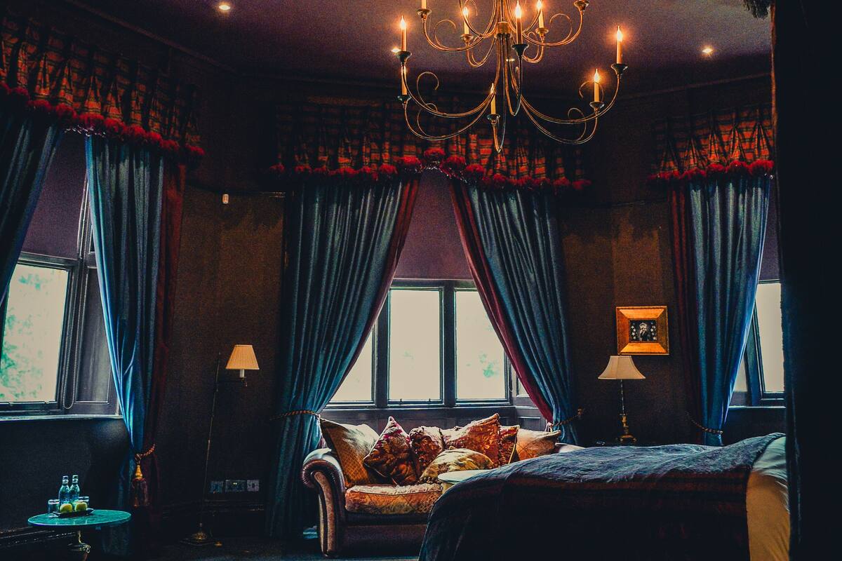 A hotel room with a large bed, a chandelier, and curtains.