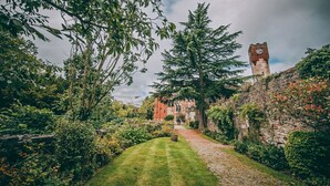 A historic building with a clock tower, surrounded by lush greenery and a well-maintained lawn. - Ruthin Castle Hotel (Ruthin)