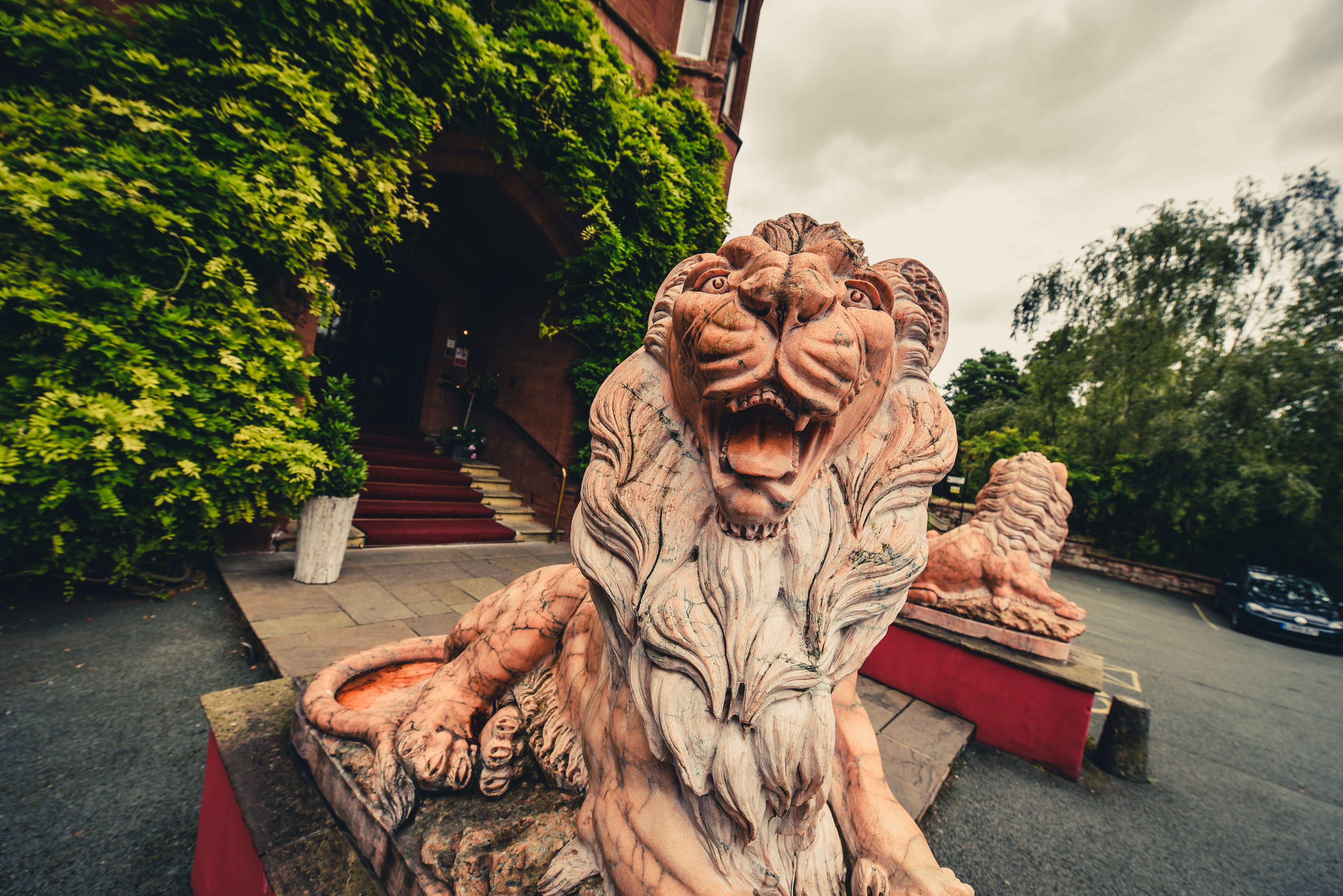Escultura de león de piedra en un patio con un edificio al fondo.