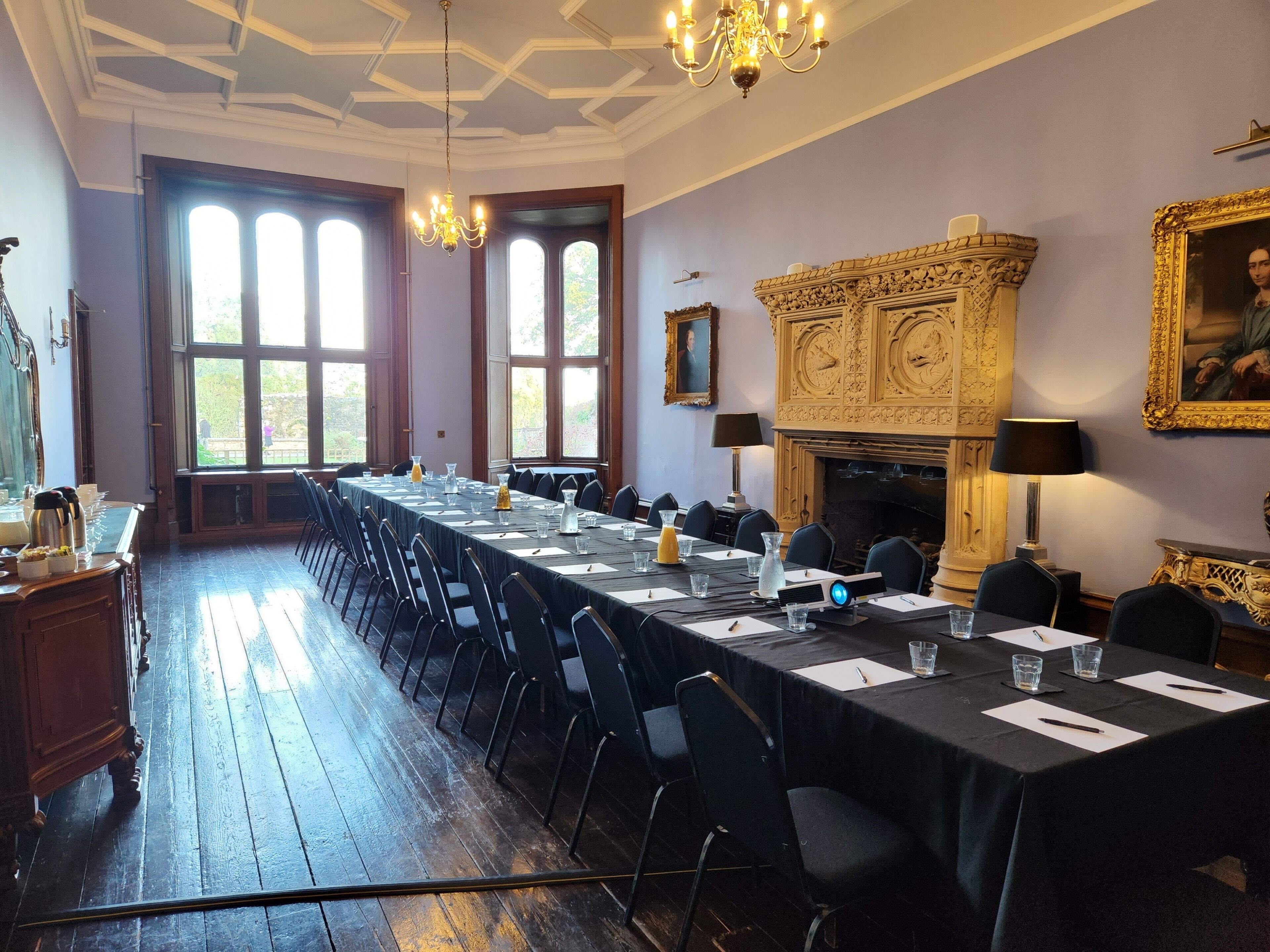A formal meeting room with a long table, chairs, and a fireplace.
