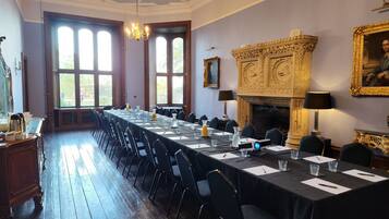 A formal meeting room with a long table, chairs, and a fireplace.