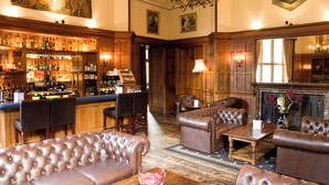 A bar area with a variety of liquor bottles, leather seating, and a fireplace. - Ruthin Castle Hotel (Ruthin)