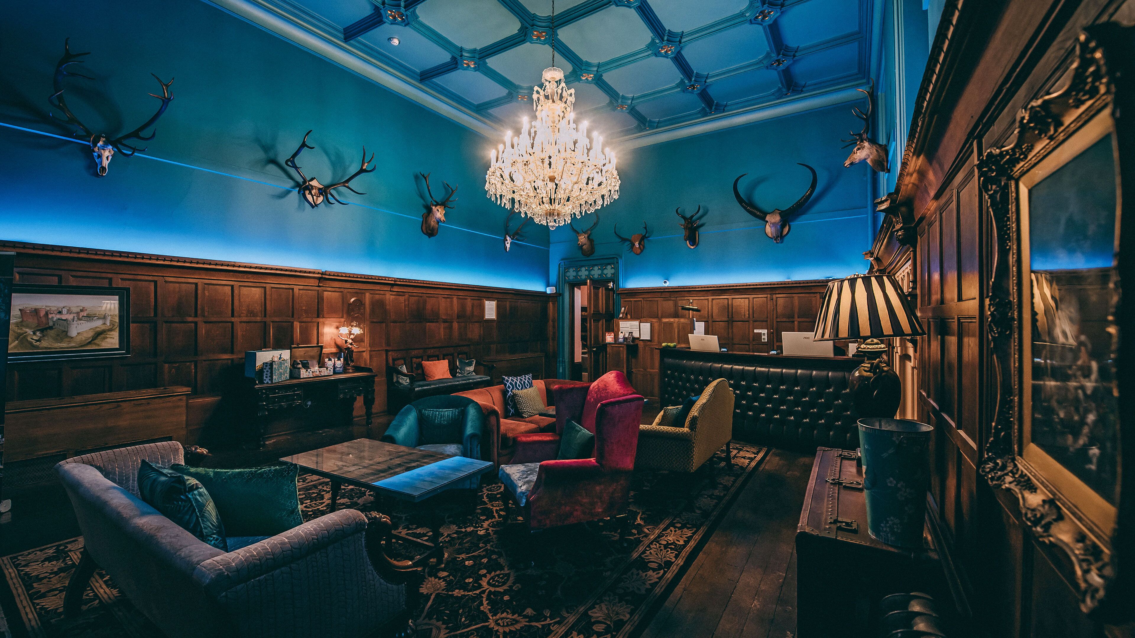 Um quarto com painéis de madeira, um candelabro e crânios de animais fixados nas paredes.