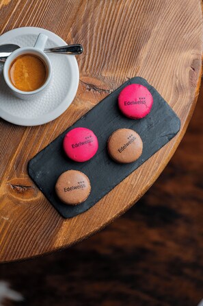 Indulge in a sweet treat at this charming table setting, complete with a selection of Edelweiss macaroons and a warm cup of coffee.