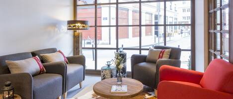 A modern living room with a large window, a round wooden coffee table, and two sofas.