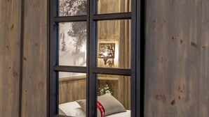 Una ventana con vista a una cama y una pared con un panel decorativo.